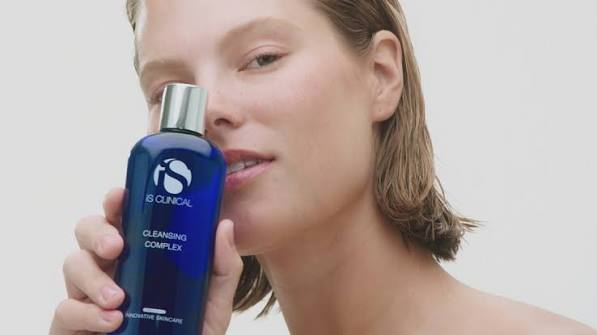 woman holding iS Clinical cosmetic near her face